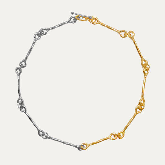 A two-tone choker necklace with one side plated in gold and the other in silver.