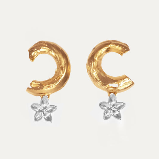A pair of earrings featuring a crescent shape with floral accents, one half of each earring plated in gold and the other in silver.