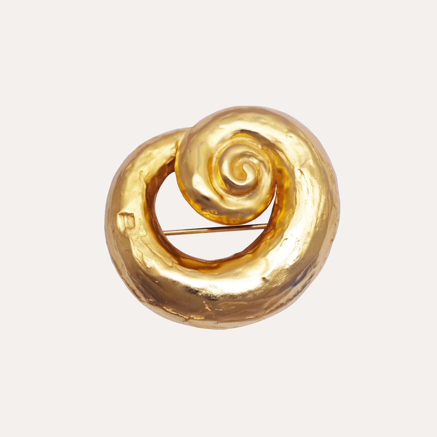 Gold spiral brooch with textured surface.