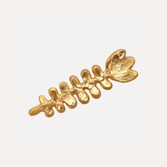 A gold-colored brooch with a floral design, featuring textured, sculptural details.